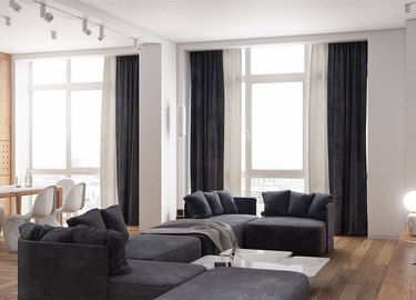 Clutter free living room with white walls, dark curtains and a dark couch.