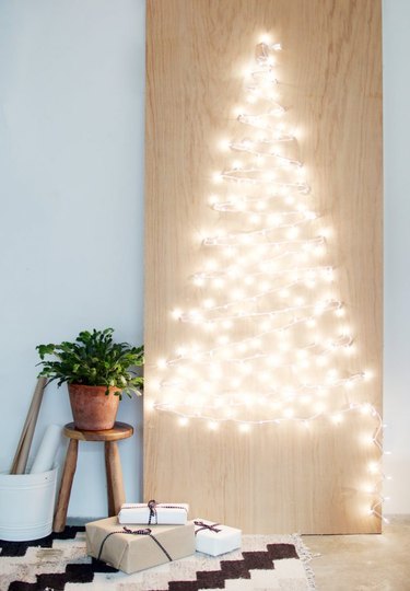 Christmas tree made from small string lights on plywood panel