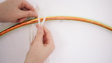 Tying yarn strands onto hula hoop