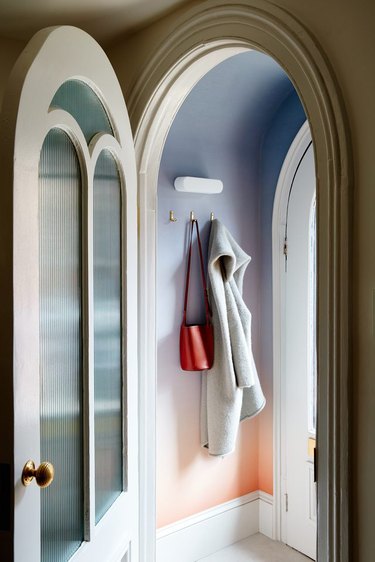 Ombre walls in a round entryway with a coat and purse hanging from hooks