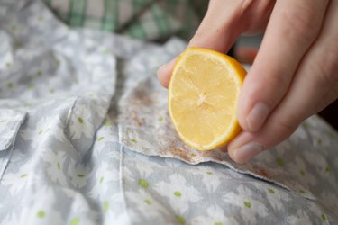 Hands squeezing a lemon over stained fabric