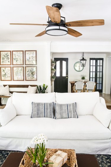 Farmhouse living room with white sofa and black ceiling fan.