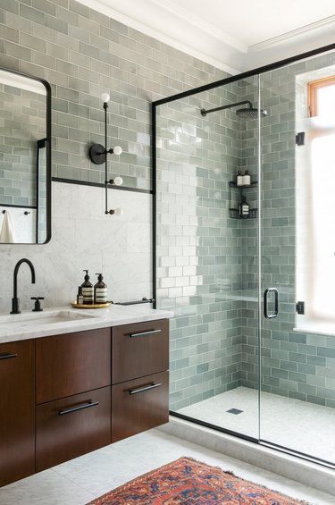 green midcentury bathroom tile with black accents and dark wood vanity cabinet
