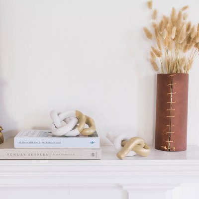 two diy clay knot sculptures on mantel with mirror, books and dried flowers