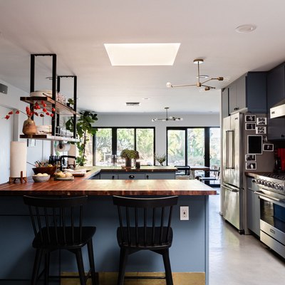 kitchen with blue cabinetry, concrete floors, skylight, windows overlooking trees