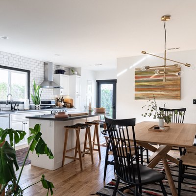 open living and dining room with island, plants, wood table, modern pendant light