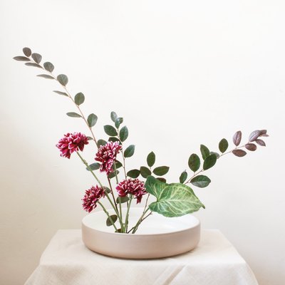 diy ikebana flower arrangement of burgundy flowers and long green leaves