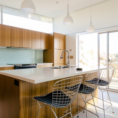 sunny kitchen with eat-in island, wire chairs, wood cabinetry, white floor