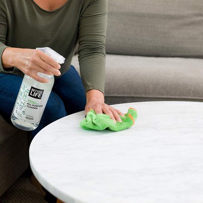 person using Better Life All-Purpose Cleaner to clean table