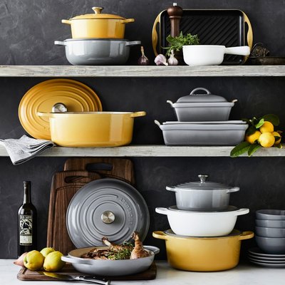 grey, yellow, and white Le Creuset cookware on shelves