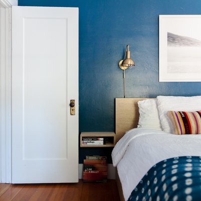 bedroom idea with blue wall and brass wall sconce at bed