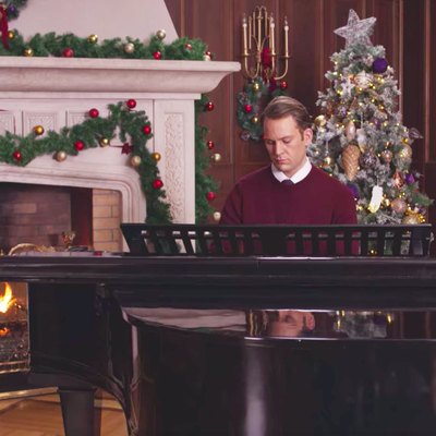 man sitting in front of piano in holiday decorated room