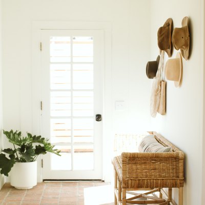 entryway idea with hats displayed on wall above accent bench with terra cotta flooring