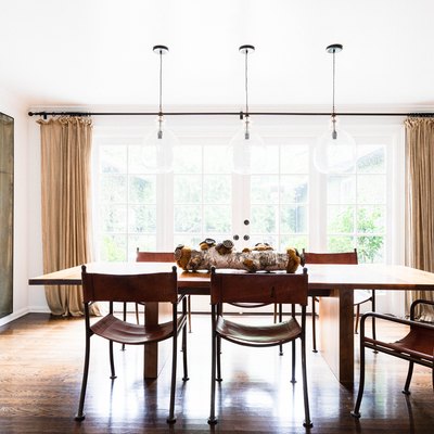 neutral dining room idea with mirrored accent wall and storage cabinet and floor to ceiling drapery