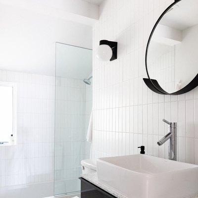 White tile in bathroom with round black mirror