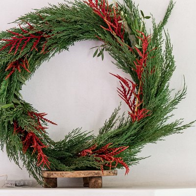 Faux holiday wreath with cedar on mantel.