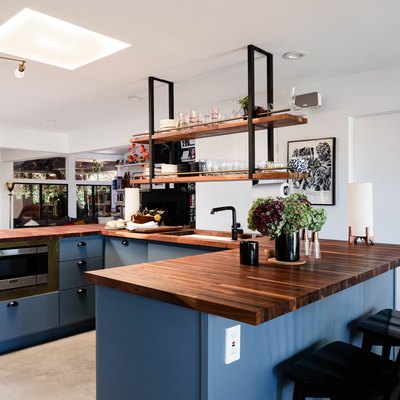 open concept kitchen with blue kitchen island and concrete flooring