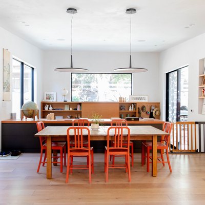 open concept view of dining room table with orange chairs and living room.