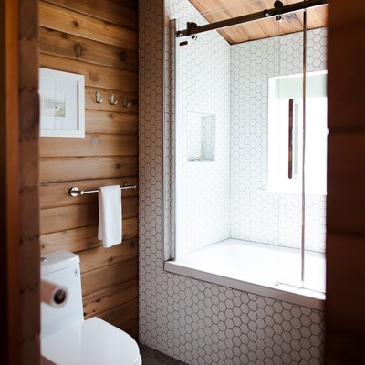 bathroom view with shower/tub combo, toilet and wood-paneled walls and ceilings