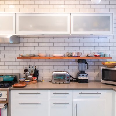 kitchen with subway tile, open shelving, white cabinetry, floral wallpaper