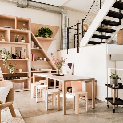 open living space with exposed stairs, chair, plywood shelving