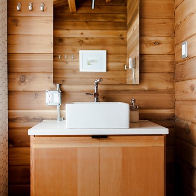 bathroom sink and vanity cabinets on wood wall background with electrical outlet