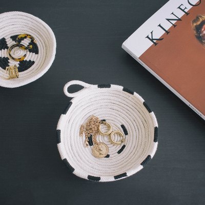 Two DIY painted cotton rope bowls on table with jewelry inside