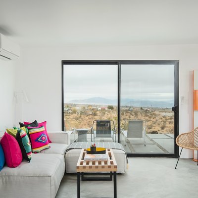 Minimal desert-inspired living room with light gray couch and neon geometric throw pillows