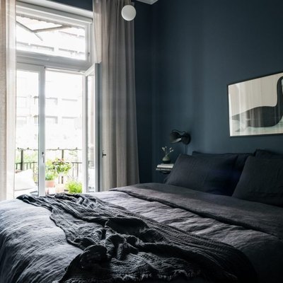 dark minimalist bedroom with deep blue wall paint and white curtains