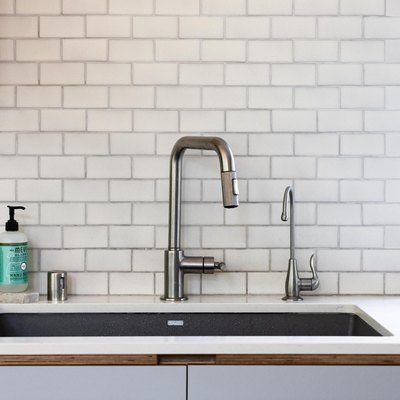kitchen sink and faucet with white subway tile backsplash and garbage disposal buttons