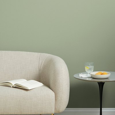 beige couch near black table with green wall in the background