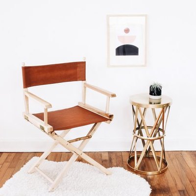 Leather director's chair next to brass side table on white rug
