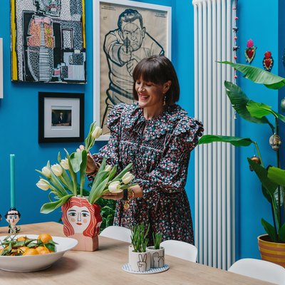 Zoe Anderson arranging tulips in her bright blue dining room