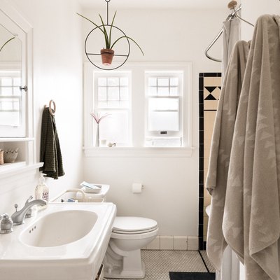 white bathroom with pedestal sink, toilet and hanging towels