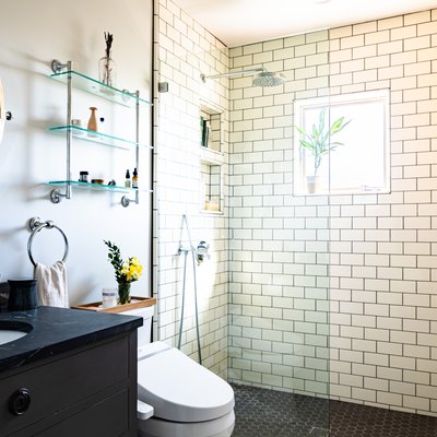 bathroom with open shower with subway wall tile, toilet and bathroom vanity sink in the picture