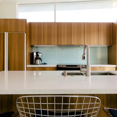 kitchen with natural wood cabinetry, kitchen island with white stone countertop and glass backsplash
