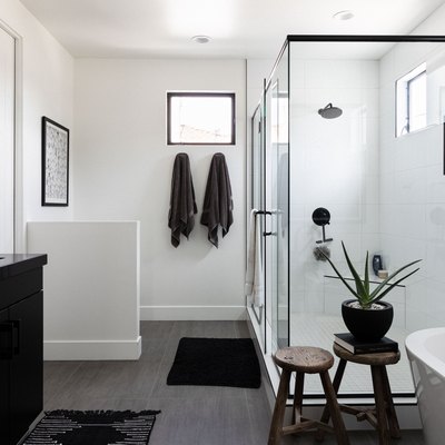 black and white bathroom with large shower, black bathroom vanity and sink and stand-alone tub