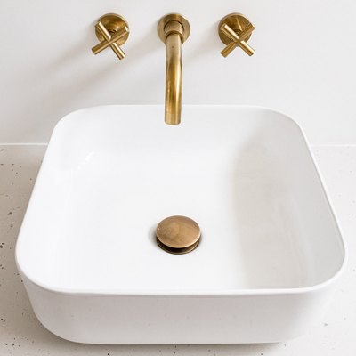 white ceramic vessel sink, gold stopper and faucet, wall outlet