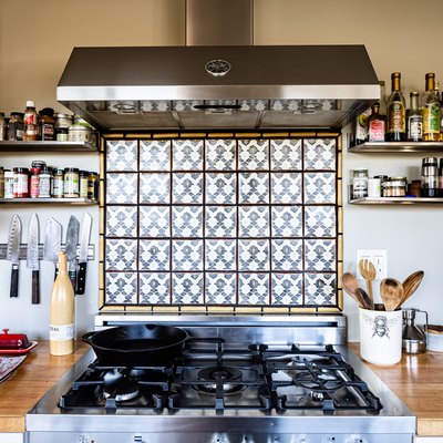 view of kitchen stove, accent backsplash and range hood