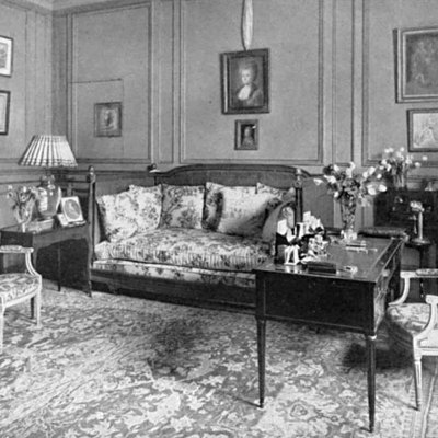 black and white photograph of a living room space with chairs, couch, and framed artworks