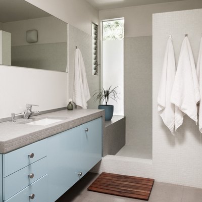 blue and grey bathroom vanity cabinet with sink, walk-in shower and three towels on hooks