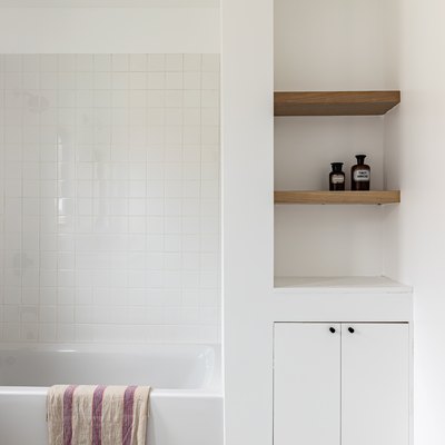 white tile, white combination tub and shower, built-in wood shelves