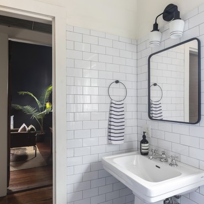 bathroom with white subway tile wall, black square mirror, black light fixture, pedestal sink, black and white striped hand towel