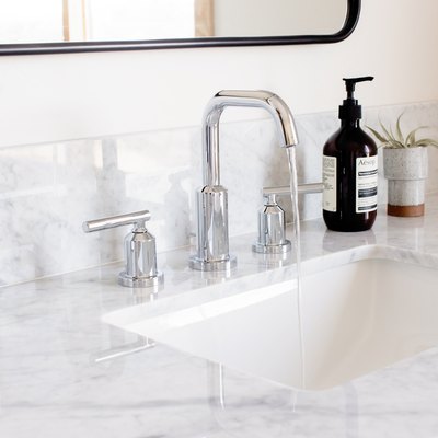 marble vanity countertop, silver faucet, mirror with black trim, toothbrush holder