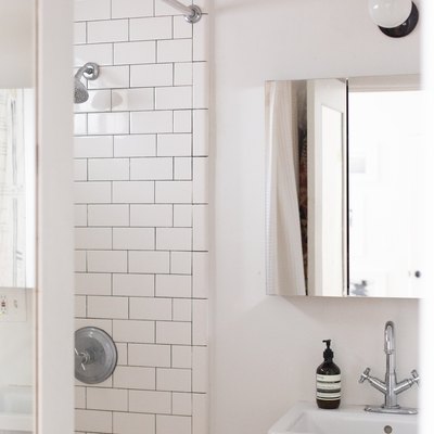 white ceramic console sink, mirrored medicine cabinet, white subway tile shower wall, round white light fixture