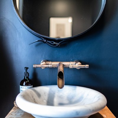 A white sink basin with a contemporary faucet with a blue bathroom wall