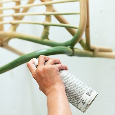 Spray painting rattan chair with green paint.