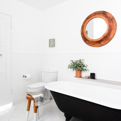 bathroom with black clawfoot tub, toilet and circular mirror
