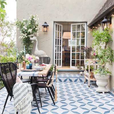 backyard patio with patterned tile and woven rattan chairs with open French doors