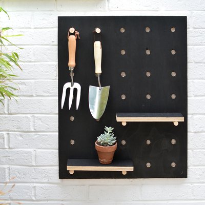Painted wooden pegboard with garden tools